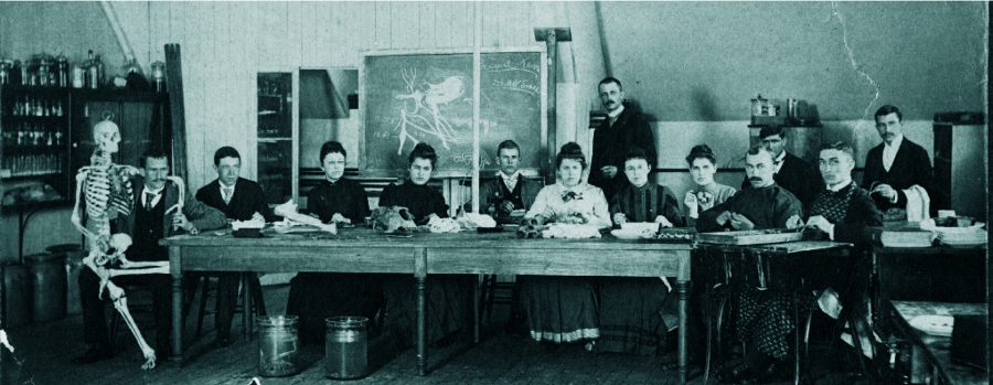 black and white photo of old swarthmore anatomy classroom with skeleton and people at table